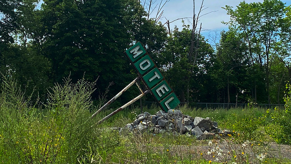 Pancarte de motel dans un champs à Laval.